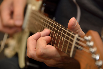 Foto von einer Gitarre, die gerade gespielt wird.